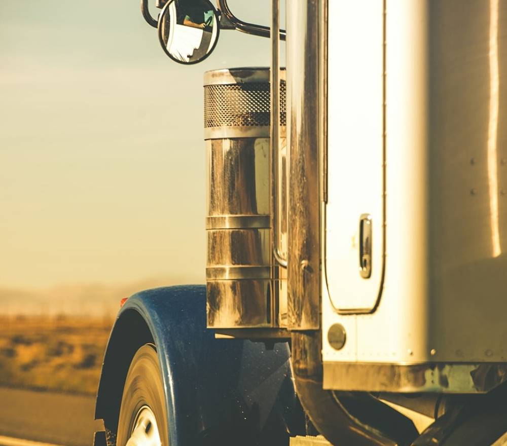 A close up of a truck, with the reflection of the driver in the side mirror in focus