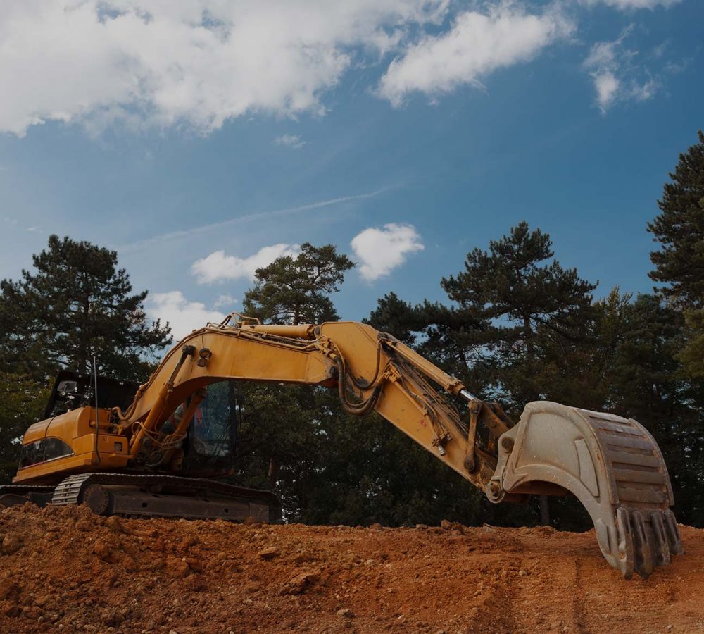 An excavator using its arm to perform earthworks on a site